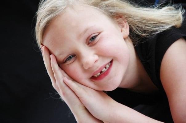 Jess as a young child, smiling in a portrait photograph