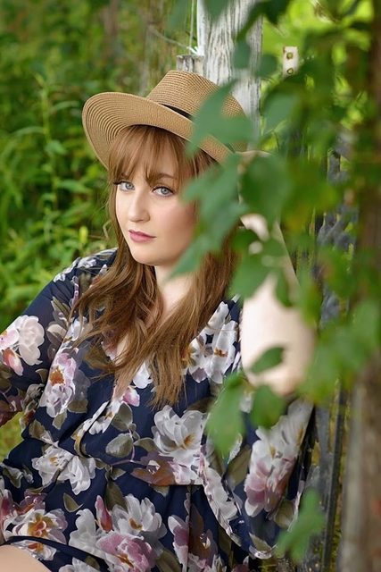 Jess Latham outdoors in a wide-brimmed hat and floral dress